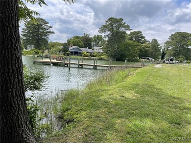 View of dock with a lawn and a water view
