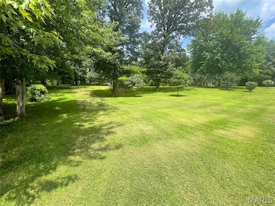 View of grassy yard featuring view of wooded area