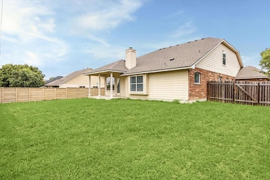 Back of house featuring brick siding, a chimney, 