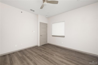 Spare room with a ceiling fan, wood finished floors, visible vents, and baseboards