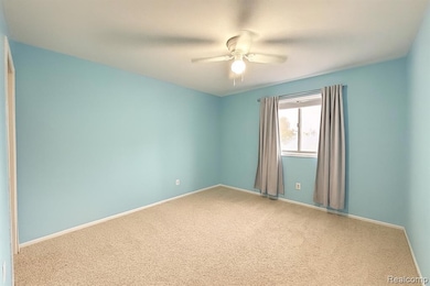 Carpeted empty room with baseboards and a ceiling fan