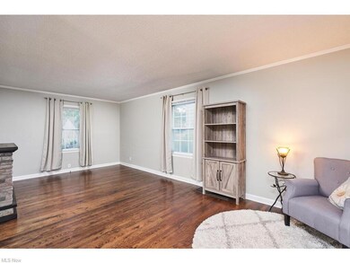 Living area with ornamental molding, wood-type flooring, a healthy amount of sunlight, and a textured ceiling