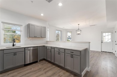 Kitchen featuring gray cabinetry, plenty of natural light, a peninsula, light wood-type flooring, and recessed lighting