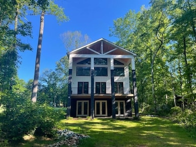 Back of property with french doors, a lawn, and a balcony