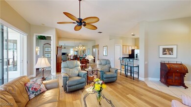 Living area with a ceiling fan, light wood-type flooring, and a chandelier