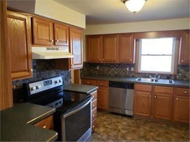 Kitchen featuring brown cabinetry, appliances with stainless steel finishes, and dark countertops