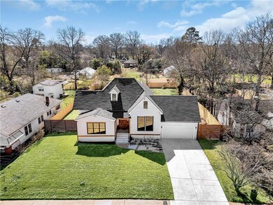 View of front of house with concrete driveway, an attached garage, brick siding, roof with shingles, and view of wooded area
