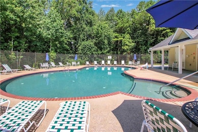 Community pool featuring a patio and view of wooded area