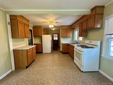 Kitchen with white appliances, light countertops, brown cabinetry, a ceiling fan, and ornamental molding