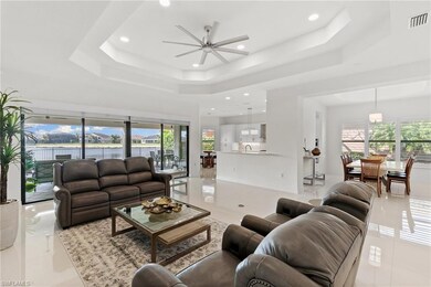 Living room featuring a raised ceiling, a ceiling fan, light tile patterned flooring, plenty of natural light, and recessed lighting