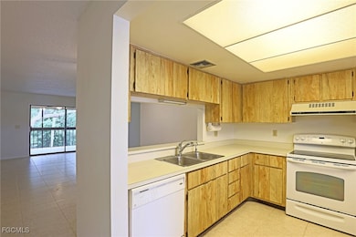 Kitchen featuring light tile patterned floors, white appliances, light countertops, extractor fan, and a textured ceiling