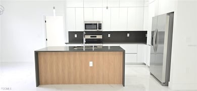 Kitchen featuring appliances with stainless steel finishes, dark stone countertops, modern cabinets, and light marble finish floors