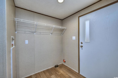 Laundry area with a textured ceiling, wood finished floors, and laundry area