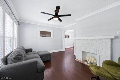 Living room featuring ornamental molding, dark hardwood / wood-style flooring, ceiling fan, and a fireplace