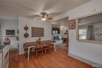 Dining space with wood finished floors, a ceiling fan, a brick fireplace, and lofted ceiling