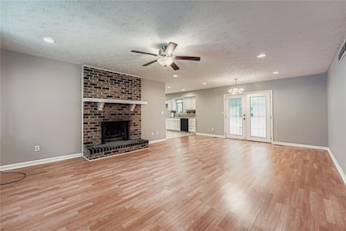 Unfurnished living room featuring a fireplace, recessed lighting, a textured ceiling, light wood-style flooring, and a chandelier
