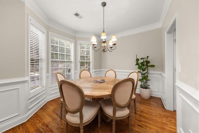 Dining room with a chandelier, plenty of natural light, a wainscoted wall, a decorative wall, and wood finished floors