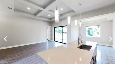 Kitchen featuring a kitchen island with sink, hanging light fixtures, light wood finished floors, light stone countertops, and open floor plan