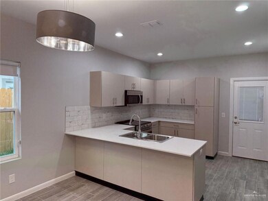 Kitchen with kitchen peninsula, pendant lighting, light hardwood / wood-style floors, and sink