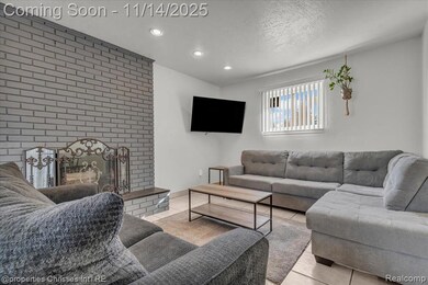 Living area with tile patterned floors, a textured ceiling, recessed lighting, and a brick fireplace