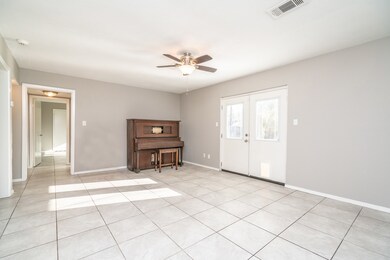 An alternate view of the family room highlights the split floor plan with the hallway leading to the first floor bathroom and master bedroom. A pair of double doors with sunlit windows open to the large wood deck and sprawling backyard.