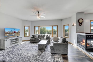 Spacious living room with beautiful views of the backyard and woods features a cozy 3 sided gas fireplace.