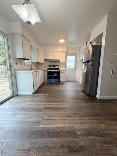Kitchen featuring light countertops, dark wood-style floors, fridge, and white cabinets