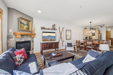 Living room with wood finished floors, a stone fireplace, and recessed lighting