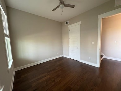 Unfurnished bedroom with dark wood-style flooring, multiple windows, and ceiling fan