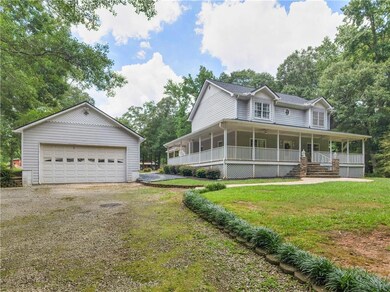 View of front facade with driveway, a porch, a front lawn, an outdoor structure, and a garage