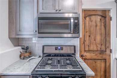 Kitchen featuring stainless steel microwave, range with gas stovetop, and tasteful backsplash