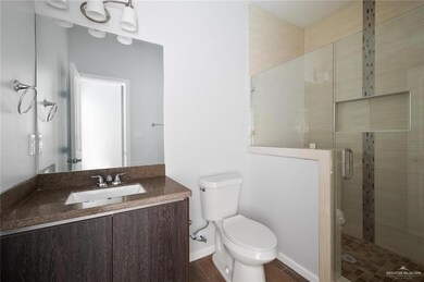 Bathroom with toilet, vanity, hardwood / wood-style flooring, and a shower with door