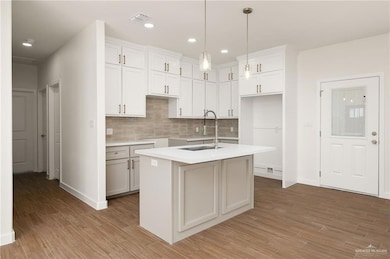Kitchen featuring backsplash, white cabinetry, light wood finished floors, decorative light fixtures, and recessed lighting
