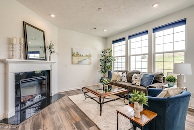 At the heart of your gathering space is a decorative fireplace with a sleek quartz hearth, creating the perfect setting for warm conversation and cozy evenings. The room is filled with natural light and offers open views of your patio and the serene green space beyond. For those quieter moments, pull-down decorative blinds allows you to soften the sunlight while still enjoying the view.