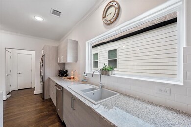 This kitchen features a modern design with sleek cabinets, granite countertops, and a spacious sink. A large window provides natural light, and there's ample counter space for meal prep.