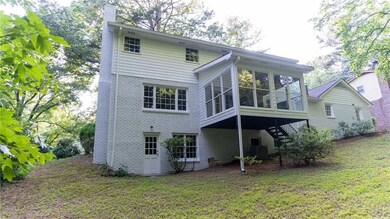Rear view of house featuring a sunroom, brick siding, stairs, and a chimney