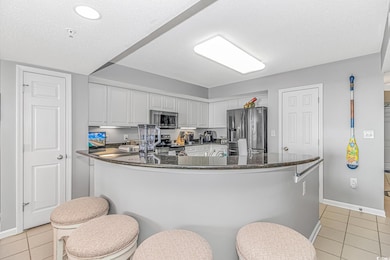 Kitchen with light tile patterned floors, white ca