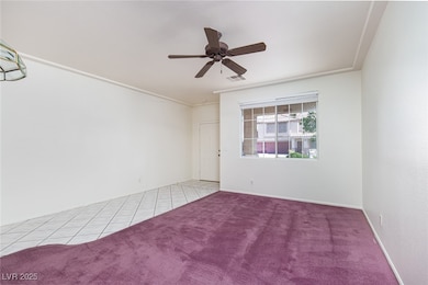 Carpeted spare room featuring ceiling fan and tile