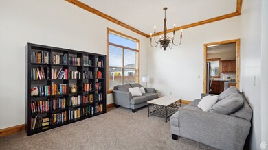 Carpeted living room with crown molding, baseboards, a healthy amount of sunlight, and a chandelier