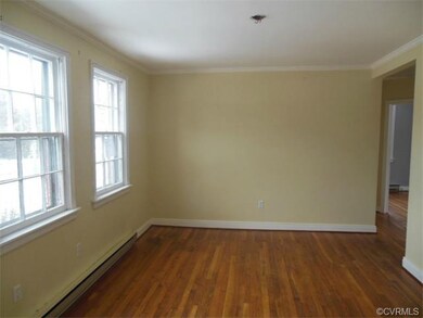 The living room is open and airy and features crown molding and beautiful wood floors.
