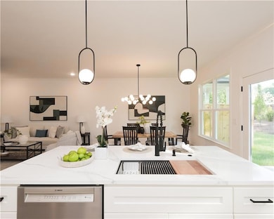 Kitchen with light stone countertops, stainless steel dishwasher, white cabinets, pendant lighting, and open floor plan