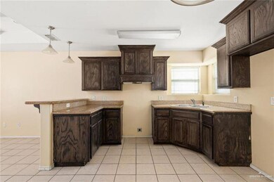 Kitchen featuring light tile patterned floors, dark brown cabinets, and a sink