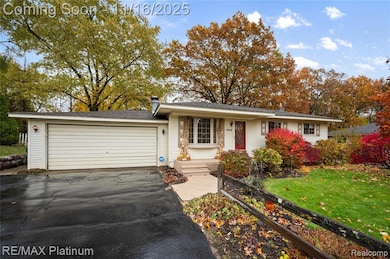 Ranch-style home featuring a front lawn, asphalt driveway, and a garage