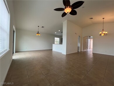 Unfurnished living room featuring arched walkways, ceiling fan, tile patterned floors, lofted ceiling, and a chandelier