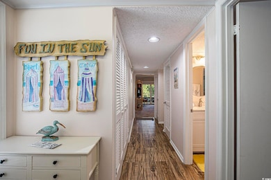Corridor featuring a textured ceiling, dark wood-type flooring, and recessed lighting