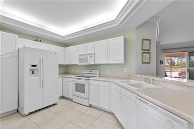 Kitchen featuring white appliances, white cabinets, light countertops, and crown molding