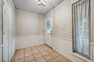 Entryway with a chandelier, crown molding, light tile patterned floors, and a textured ceiling