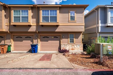 View of front facade with a garage, driveway, and stone siding