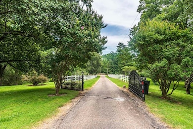 View of asphalt driveway with a gate and a gated entry