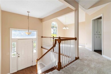 Carpeted entryway with lofted ceiling, a chandelier, and baseboards